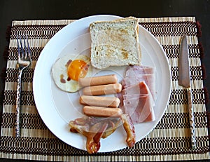 American breakfast has ham egg sausage beacon on tablemat