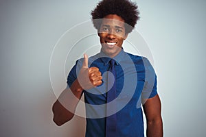 American business man with afro hair wearing blue shirt and tie over isolated white background doing happy thumbs up gesture with