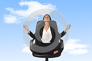 American business woman sitting at office chair in lotus posture practicing yoga and meditation