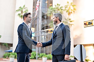 American businessman shaking hands with partner. Handshake between two business men. Two businessmen shaking hands on