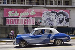American cars under a cuban propaganda billboard