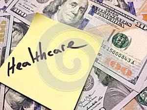 American cash money and yellow paper note with text Healthcare photo