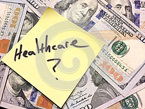 American cash money and yellow paper note with text Healthcare question mark photo