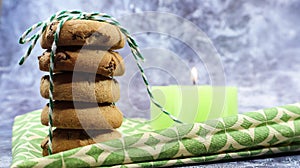 American chocolate chip cookies in a stack tied with thread on a green napkin and a candle. Traditional rounded crunchy dough with