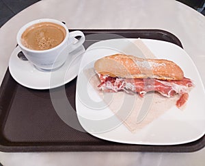 American cofee and iberic ham sandwich in a withe dishes.