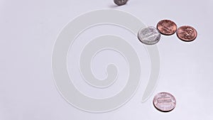 American coins spin on a white table. One cent, a quarter dollar. Copy space. Heads or tails. Hand raking in money