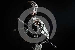 American commando in a military uniform with a weapon looks at copy space, a marine on a dark background, a member of the elite