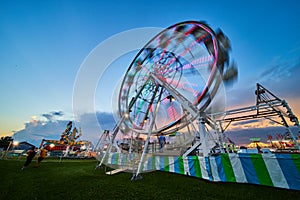 American county fair at dusk with blurred ferris wheel