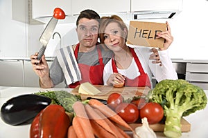 American couple in stress at home kitchen in cooking apron asking for help frustrated