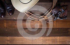 American Cowboy Items incluing a lasso spurs and a traditional straw hat on a wood plank background