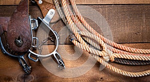 American Cowboy Items incluing a lasso spurs and a traditional straw hat on a wood plank background