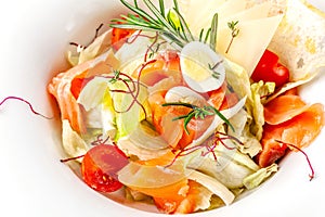 American cuisine concept. Caesar salad with salmon. White plate on a white background. Image for a menu of restaurants