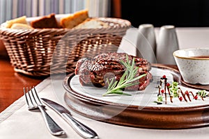 American cuisine concept. Pork steak with red tomato barbecue sauce. Serving dishes on a wooden board in a restaurant