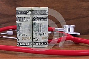 American currency and red stethoscope on wood background