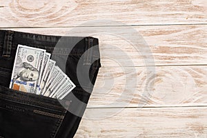 American dollar bills in jeans pocket on white wooden background with copy space for your text. Top view