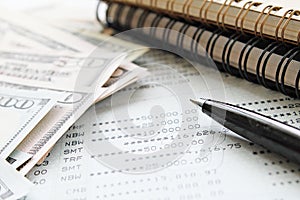 American Dollar cash money, notebook paper, pen and savings account passbook or financial statement on office desk table