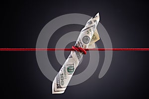 American dollar tied up in red rope knot on dark background with copy space. business finances, savings and bankruptcy concept