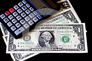 American dollars banknotes and calculator on the black table.