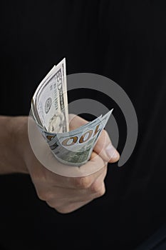 American dollars in male hands on a black background. One hundred dollar bills. Money