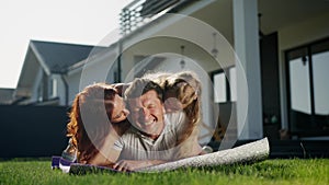 American dream family relax outdoors near the house on the lawn, lie on a purple blanket, carpet or rug. Father, mother