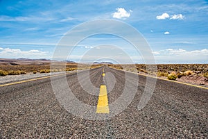 American empty desert asphalt road from low angle with mountains and clouds on background. South american highway in Atacama deser