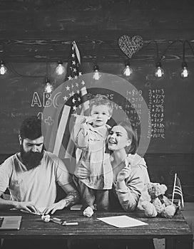 American family at desk with son making paper planes. Parents teaching son american traditions playing. Kid with parents