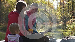 American family drinking tea having happy holiday in camping on autumn day.