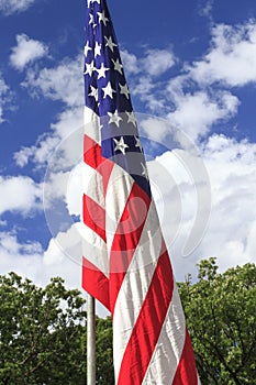 American flag against blue sky and clouds background