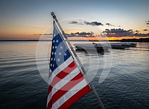 American flag on angled pole with marina and water at sunset