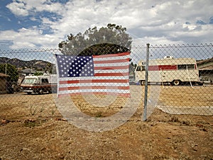 American flag attached to a chain link fence in a rural area