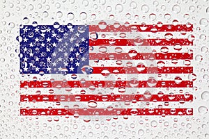 American flag behind a glass covered with rain drops.