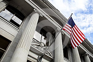 American Flag Blowing in the Wind in Front of Stone Column Building with blue sky and clouds