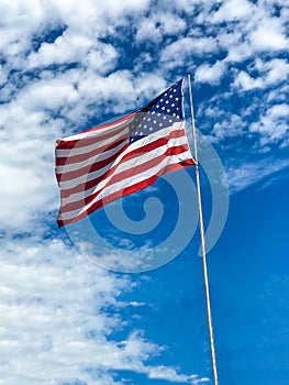 American Flag Flying against bright blue sky vertical