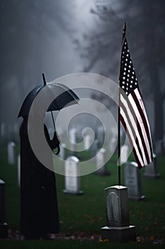 An American Flag on a Gravestone for Veteran\'s Day, Mourner with Umbrella