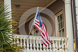 An American Flag hanging outside of a colonial era home