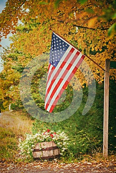 American flag hanging on the road side against autumn foliage