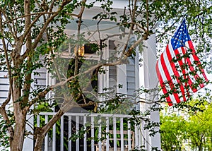 American Flag Hanging on Traditional Southern Style Home in Savannah, Georgia, USA, Surrounded by Lush Greenery and