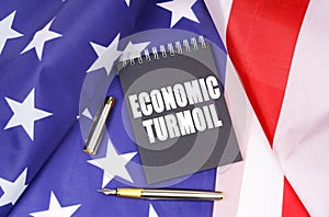 On the American flag lies a pen and a notebook with the inscription - economic turmoil