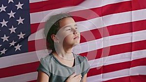 American flag. little girl holding her hand on her heart waving usa america flag behind. patriotism a faith united day