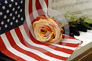 American flag on piano keys with golden rose and music score