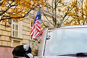 The American flag is placed on the car in autumn against a background of yellow trees. State designation of transport of officials