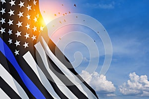 American flag with police support symbol Thin blue line on blue cloudy sky with birds