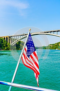 American flag and Rainbow Bridge over the Niagara River. Arch bridge connecting the United States of America and Canada