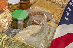 American flag, Raw cereals, jars of marinades, pasta, porridge and grains on the table. Concept: humanitarian aid with essential p