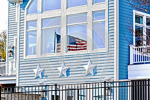 American Flag Reflection in Window of Blue House with Stars