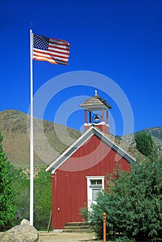 American flag waving above one room schoolhouse,