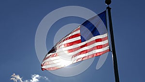 American flag waving in front of the sun in clear sky