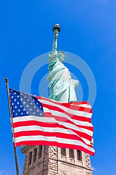 American flag waving in the wind against Statue of Liberty