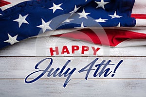 American flag on a white worn wooden background with July 4th Greeting