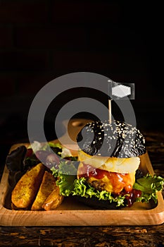 American food background of pork black hamburger with BBQ barbeque sauce on wooden plate in dark tone, slective focused